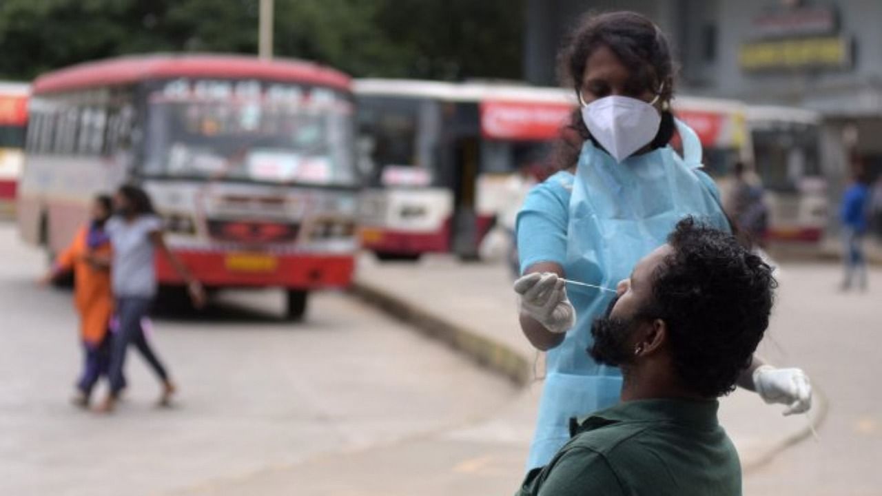 A healthcare worker collects swab samples from Kerala road transport staff at the satellite bus stand on Mysore Road, Bengaluru, on August 31, 2021. Credit: DH Photo
