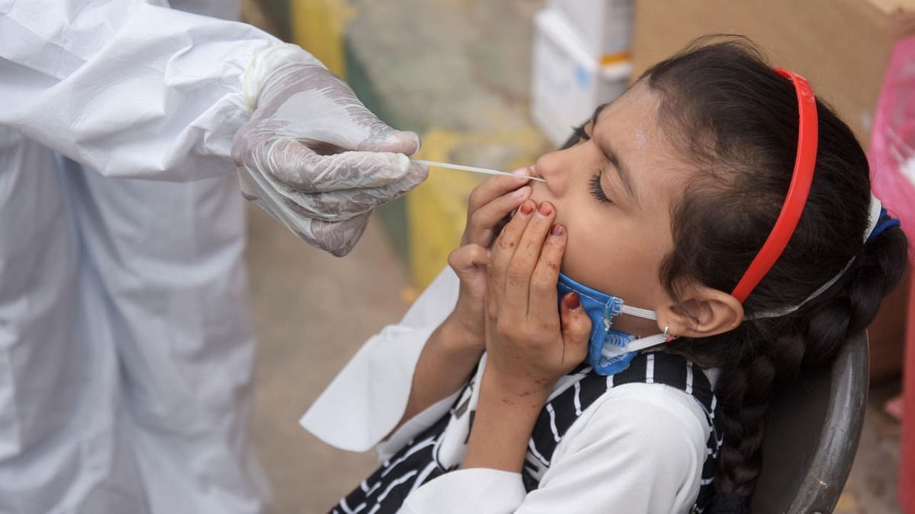 A health worker collects swab for Covid testing from a girl in Bengaluru on Thursday. Credit: DH Photo/Pushkar V