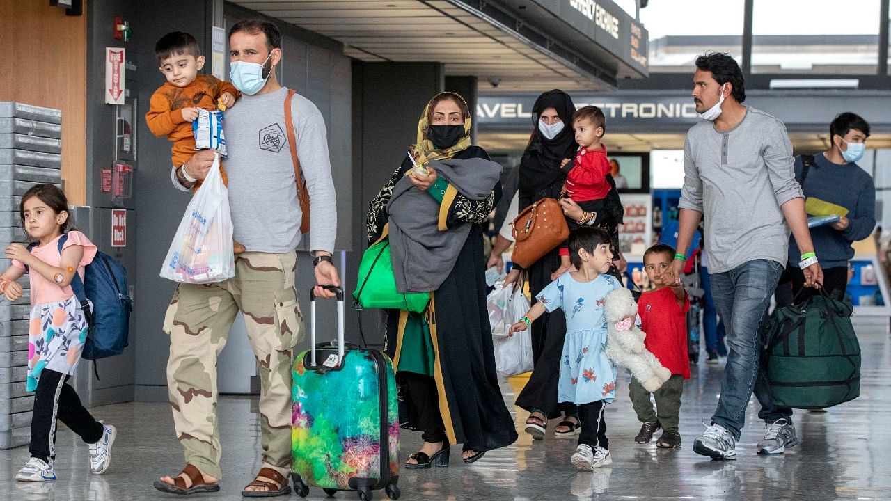 Families evacuated from Kabul, Afghanistan, walk through the terminal to board a bus after they arrived at Washington Dulles International Airport, in Chantilly, Va., on Wednesday. Credit: AP/PTI File Photo