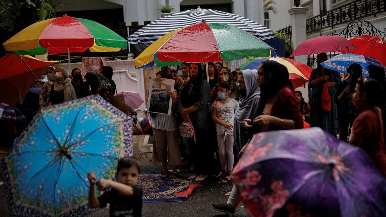 Afghan nationals hold umbrellas to cover themselves from rain as they attend a protest outside the United Nations High Commissioner for Refugees (UNHCR) office to urge the international community to help Afghan refugees, in New Delhi. Credit: Reuters photo