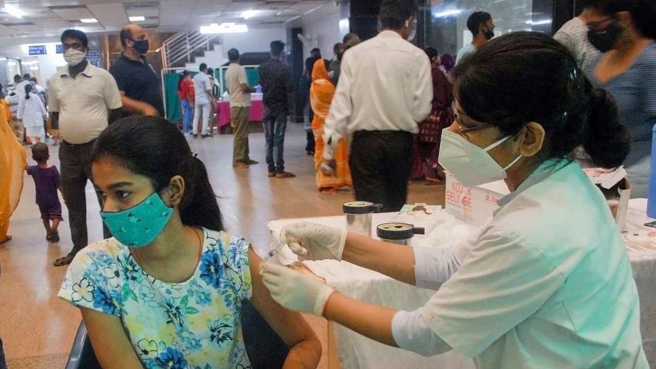 A health worker administers a dose of Covid-19 vaccine to a beneficiary, at a district hospital in Noida. Credit: PTI Photo