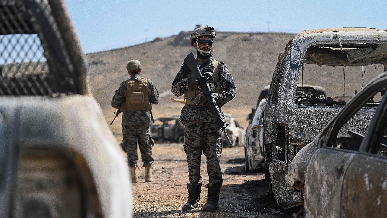 Members of the Taliban Badri 313 military unit stand besides damaged vehicles kept near the destroyed Central Intelligence Agency (CIA) base in Deh Sabz district northeast of Kabul on September 6, 2021 after the US pulled all its troops out of the country. Credit: AFP Photo