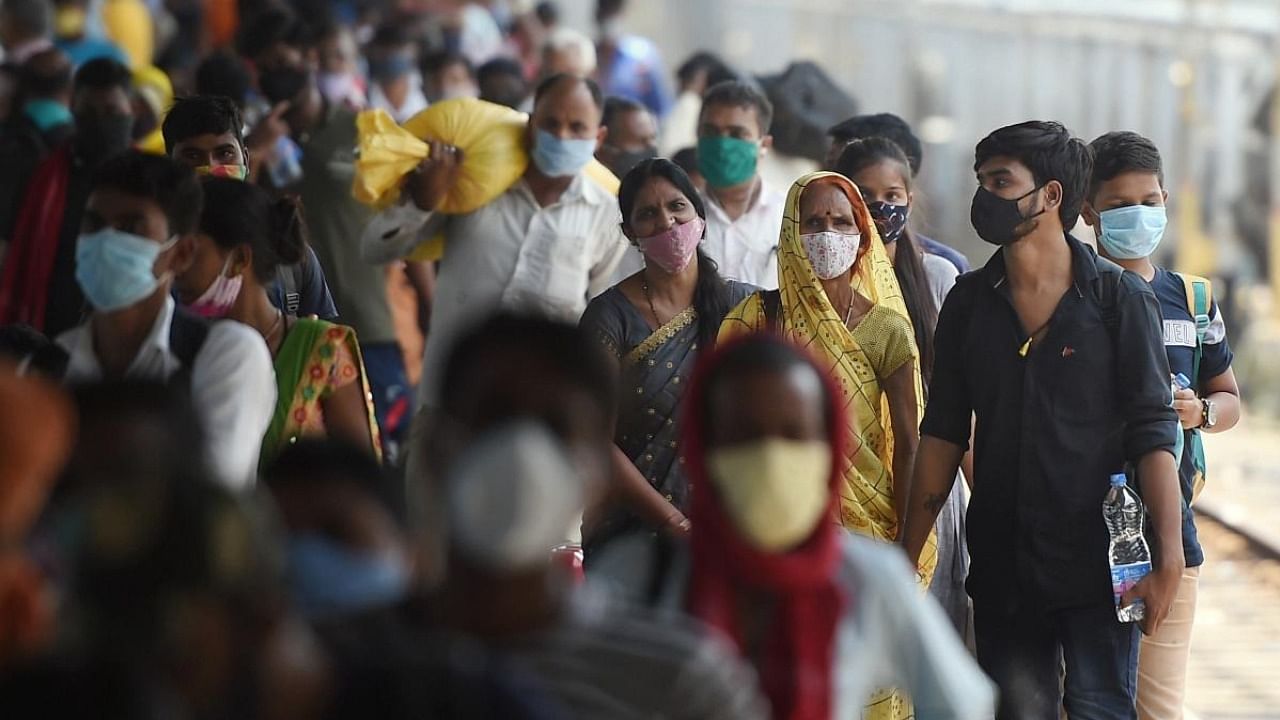 Passengers wait in queues to give swab samples for the Covid-19 testing after arriving at Lokmanya Tilak Terminus railway Station in Mumbai. Credit: PTI Photo