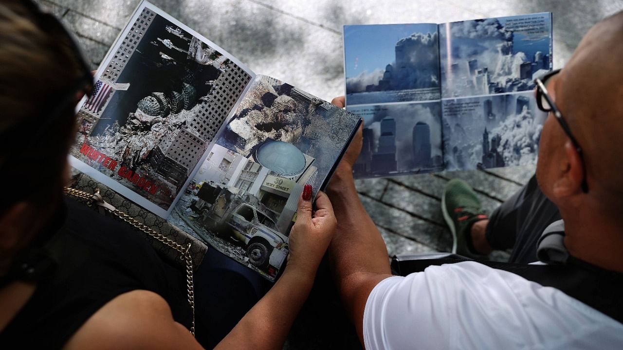 Visitors look at books about the 9/11 attacks while sitting on a bench at the September 11 Memorial and Museum. Credit: AFP Photo
