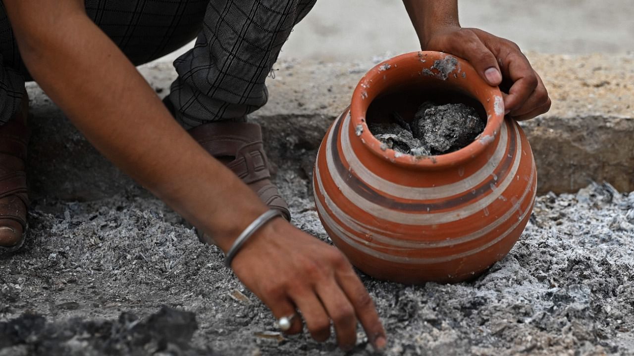 A family member collects ashes of a victim who died due to the Covid-19 coronavirus at a cremation ground in New Delhi on May 17, 2021. Credit: AFP File Photo