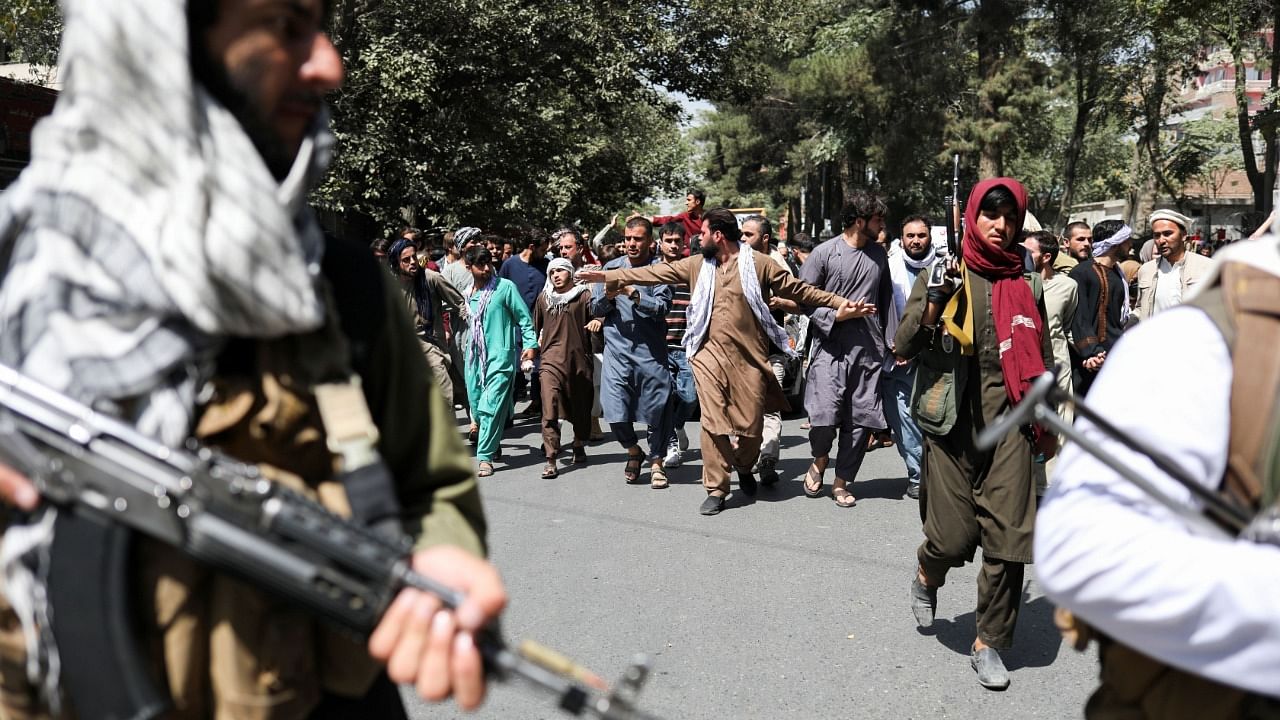 Taliban soldiers walk in front of protesters during the anti-Pakistan protest in Kabul, Afghanistan, September 7, 2021. Credit: WANA (West Asia News Agency) via Reuters