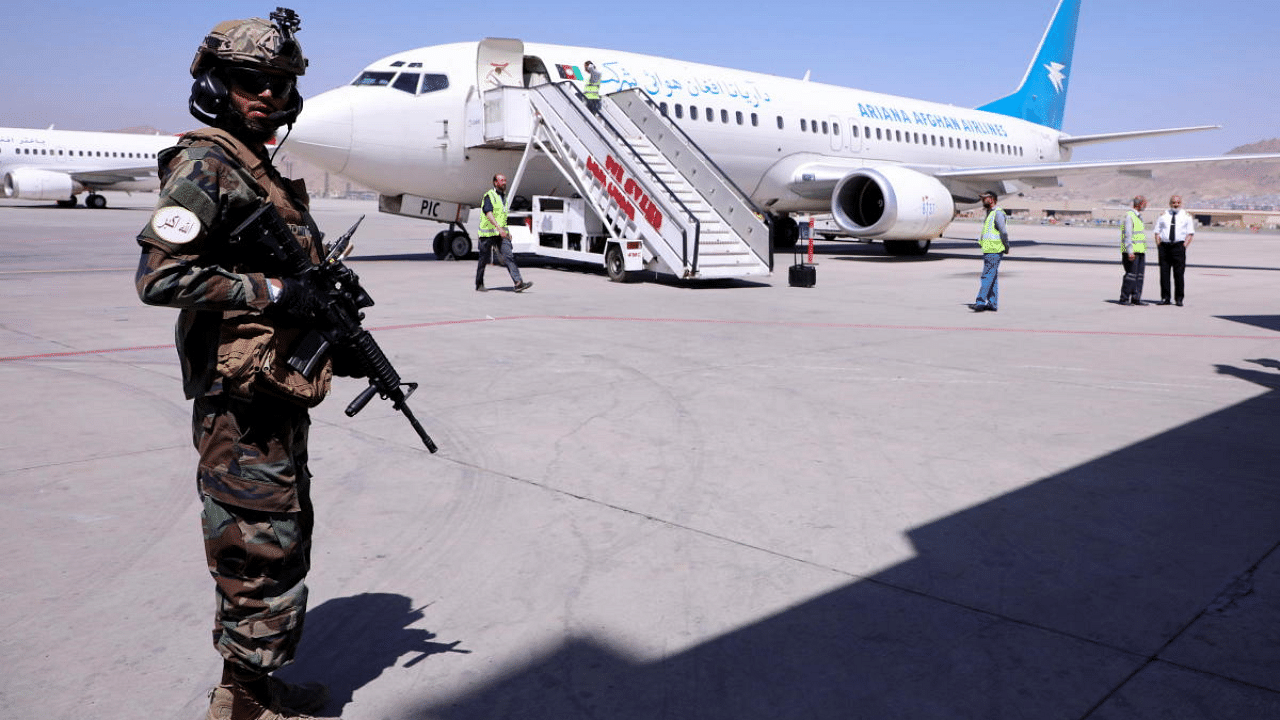 A member of Taliban forces stands guard next to a plane that has arrived from Kandahar at Hamid Karzai International Airport in Kabul, Afghanistan. Credit: Reuters Photo
