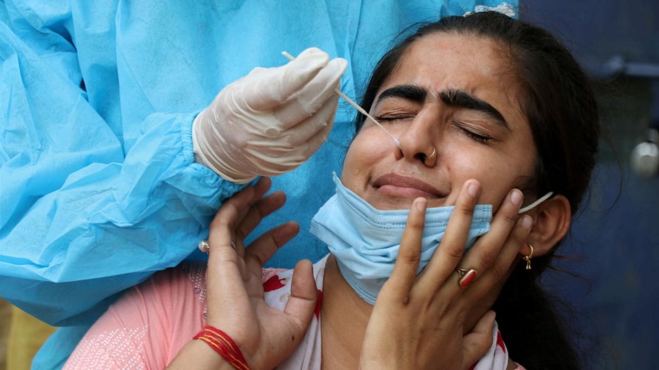 A health worker takes a swab sample of a woman for Covid-19 test, in Jammu. Credit: PTI Photo
