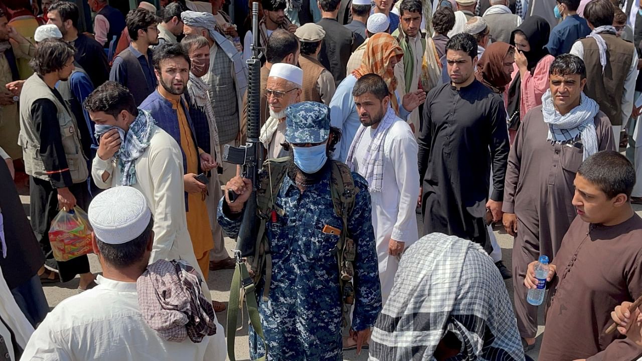 Member of Taliban security forces stands guard among crowds of people in a street in Kabul. Credit: Reuters Photo
