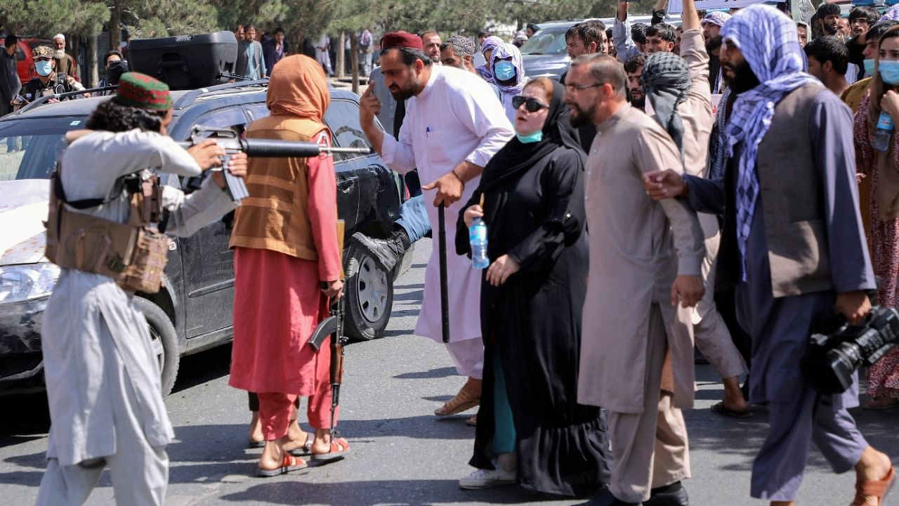 A member of the Taliban forces points his gun at protesters. Credit: Reuters Photo