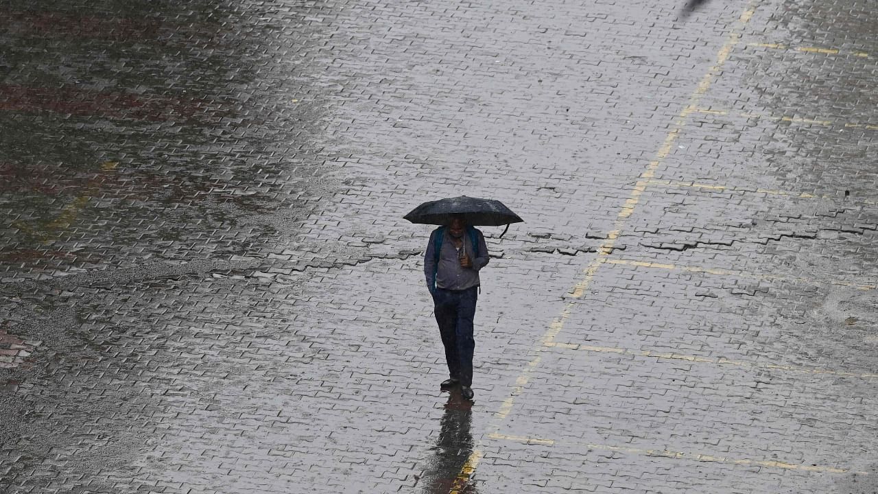 A man shelters under an umbrella while walking along a street during a downpour in New Delhi on September 11, 2021. Credit: AFP Photo