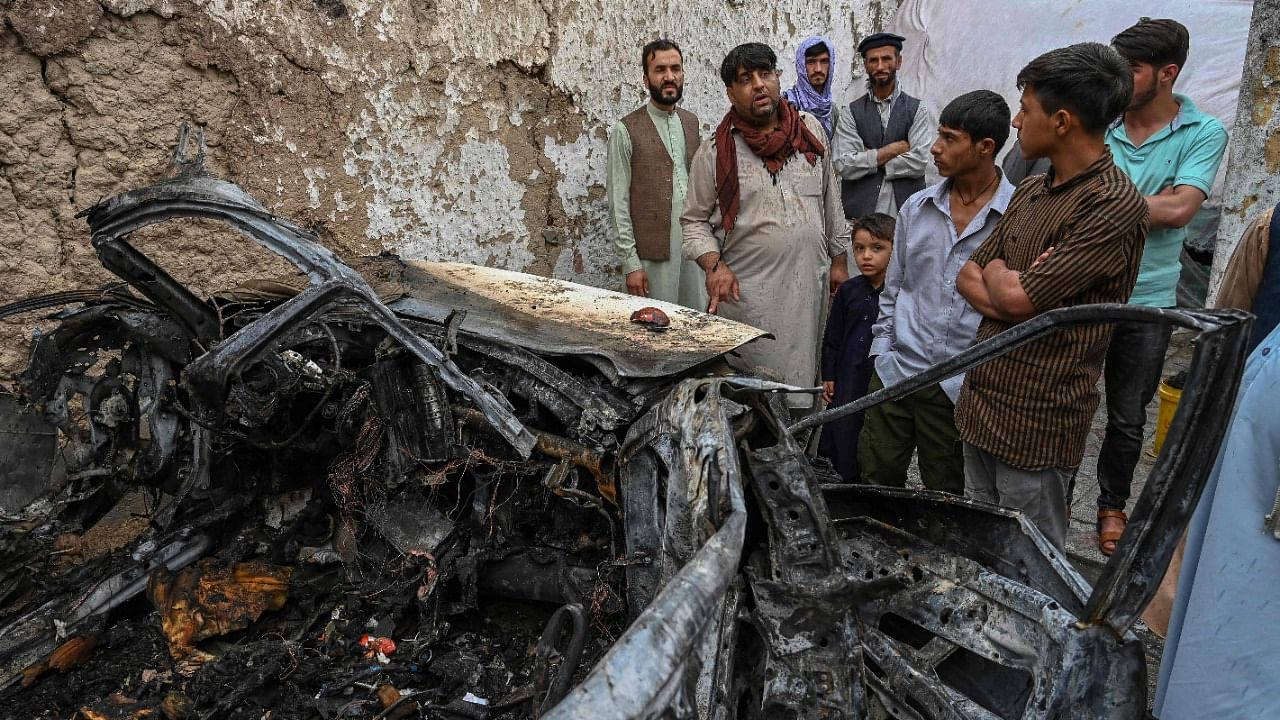Afghan residents and family members of the victims gather next to a damaged vehicle inside a house, day after a US drone airstrike in Kabul. Credit: AFP File Photo