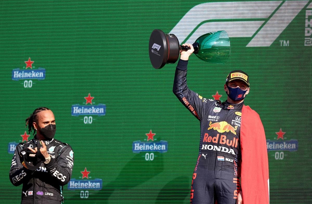 Red Bull's Dutch driver Max Verstappen (R) holds the winner's trophy as Mercedes' British driver Lewis Hamilton (L) applauds on the podium of the Zandvoort circuit after the Netherlands' Formula One Grand Prix in Zandvoort. Credit: AFP Photo