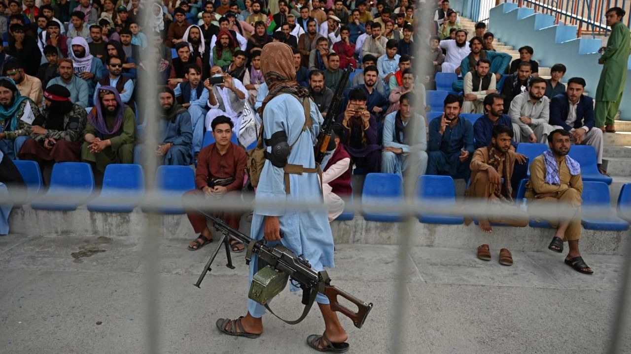 Taliban fighter walks past spectators at a cricket match. Credit: AFP Photo