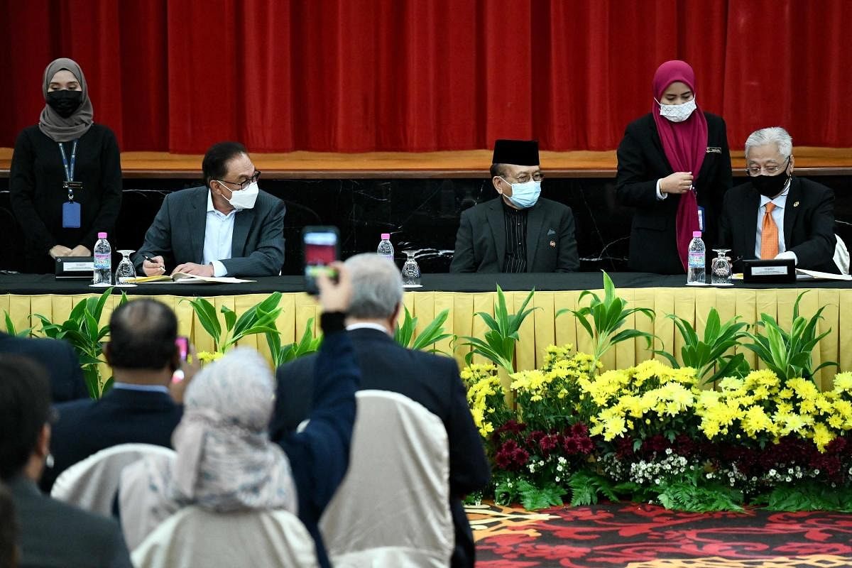 Malaysia's Prime Minister Ismail Sabri Yaakob (R) and opposition leader Anwar Ibrahim (2nd L) signing an agreement in Kuala Lumpur. Credit: AFP Photo