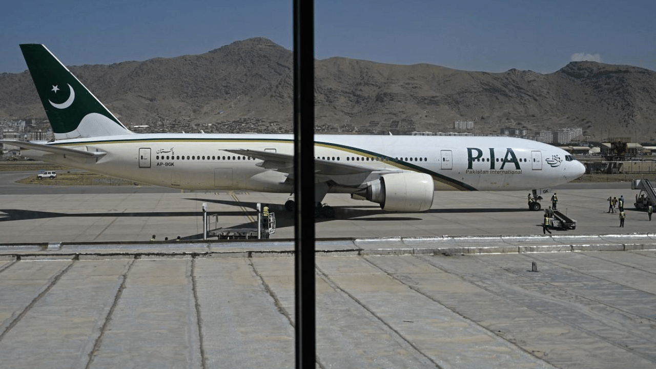 Members of ground staff stand on the tarmac beside a Pakistan International Airlines (PIA) aircraft, the first commercial international flight since the Taliban retook power last month, at the airport in Kabul. Credit: AFP Photo