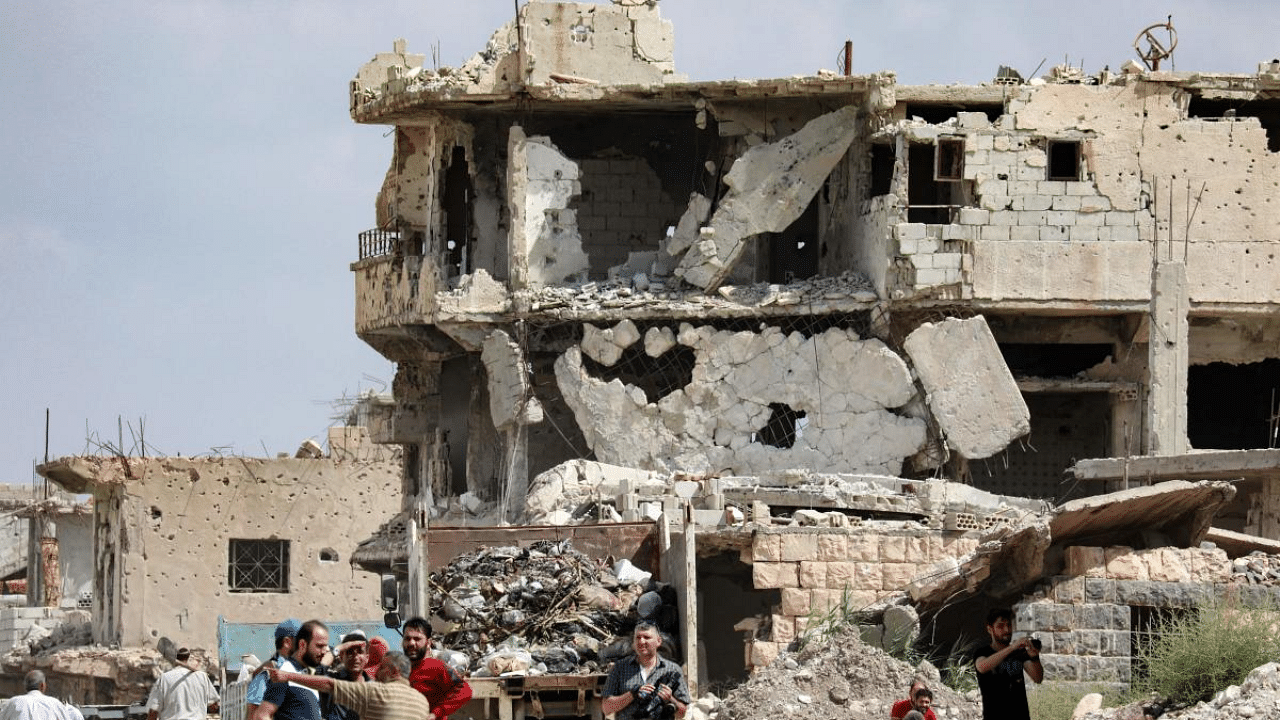 People gathered in front of a heavily damaged building in the district of Daraa al-Balad of Syria's southern city of Daraa. Credit: AFP Photo