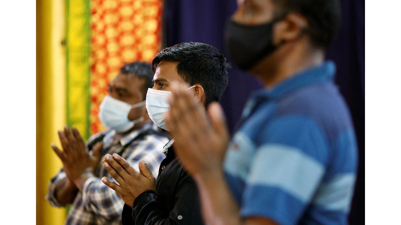 Migrant workers pray at a temple, before enjoying time off at Little India, as part of a pilot programme to allow fully vaccinated migrant workers back to the community after more than a year of movement curbs due to the coronavirus disease. Credit: Reuters Photo
