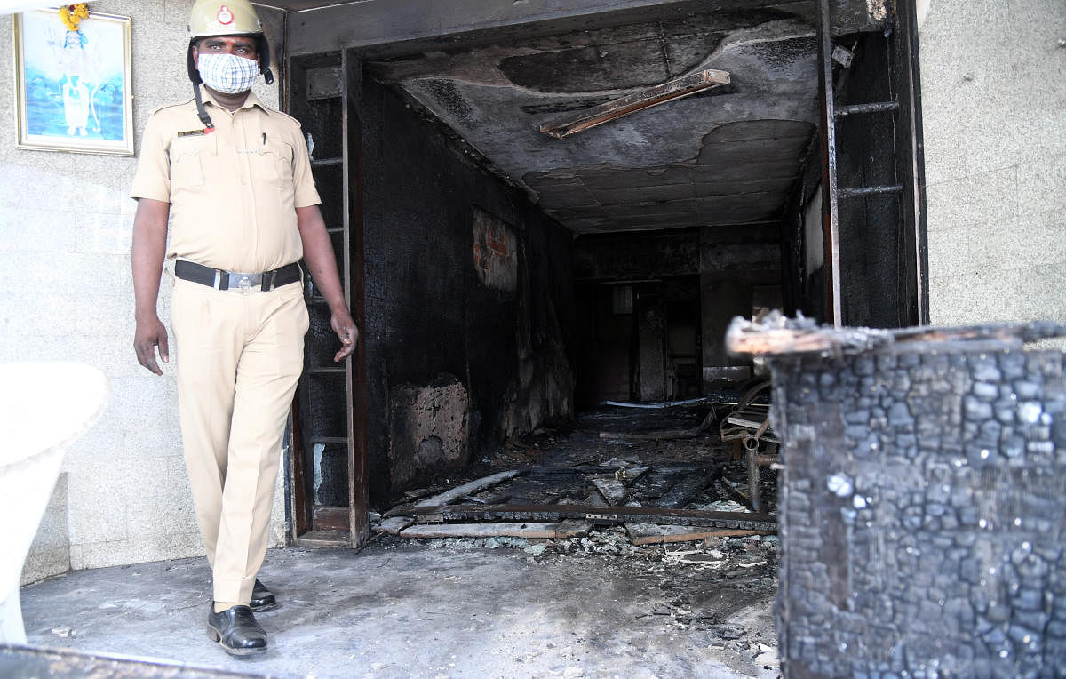 A policeman stands guard at the charred entrance of Ajantha Trinity Inn, off MG Road, in Bengaluru on Tuesday. DH PHOTO/B H SHIVAKUMAR
