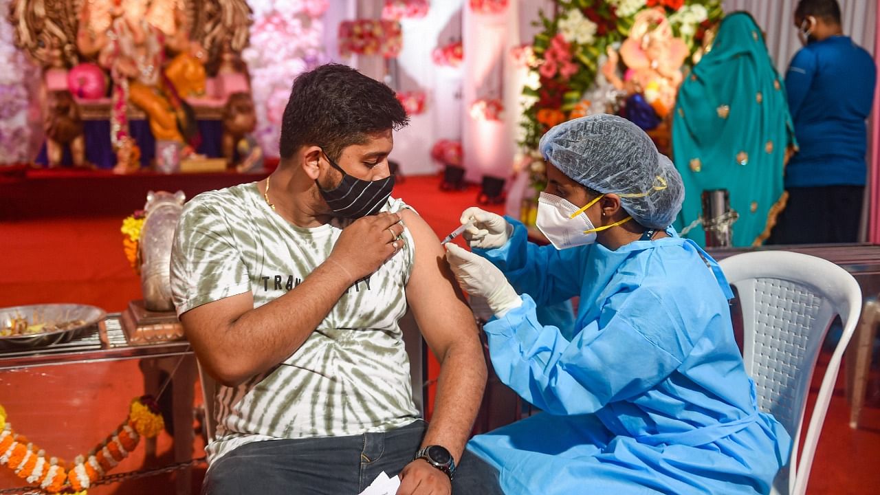 A health worker inoculates a man with a dose of the Covishield coronavirus vaccine at a Ganpati pandal in Mumbai, Wednesday, September 15, 2021. Credit: PTI Photo