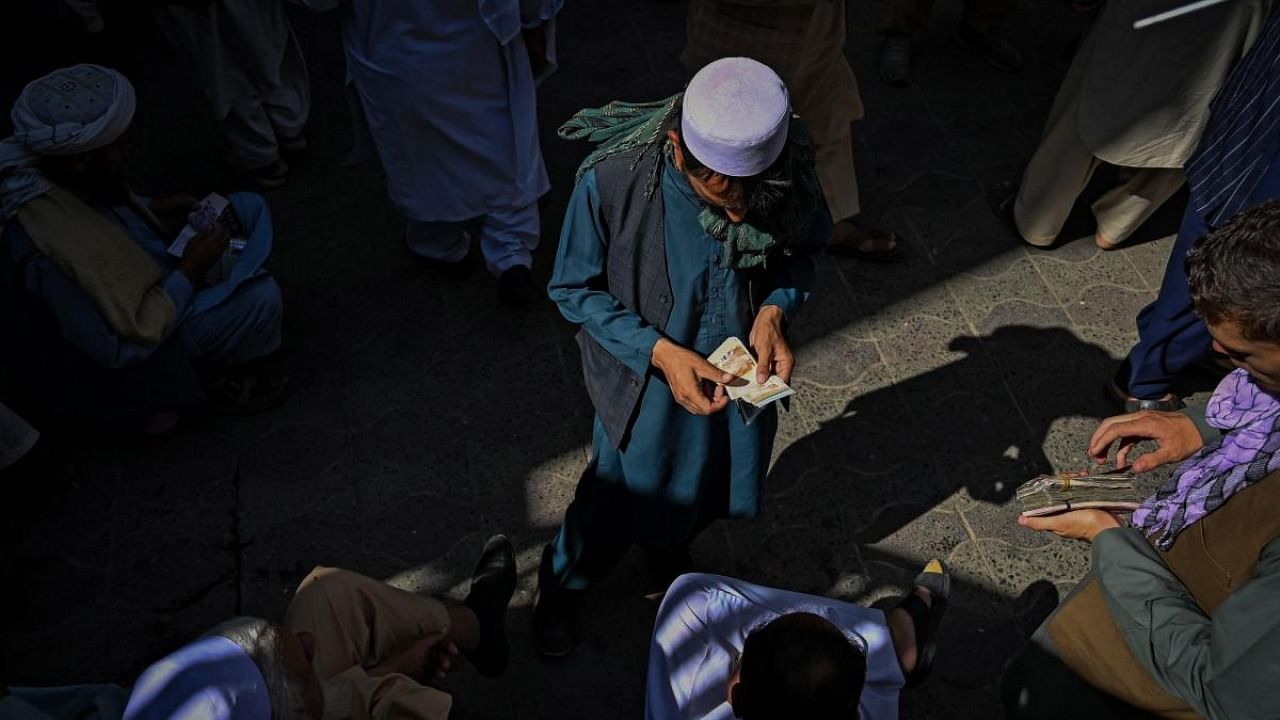 An Afghan dealer counts cash at a market area after money exchange market reopens for business in Kabul. Credit: AFP Photo
