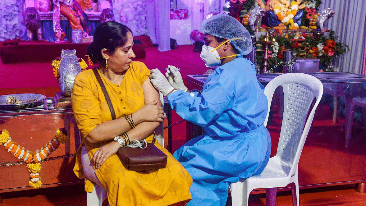 A health worker inoculates a woman with a dose of the coronavirus vaccine at a Ganpati pandal in Mumbai. Credit: PTI Photo