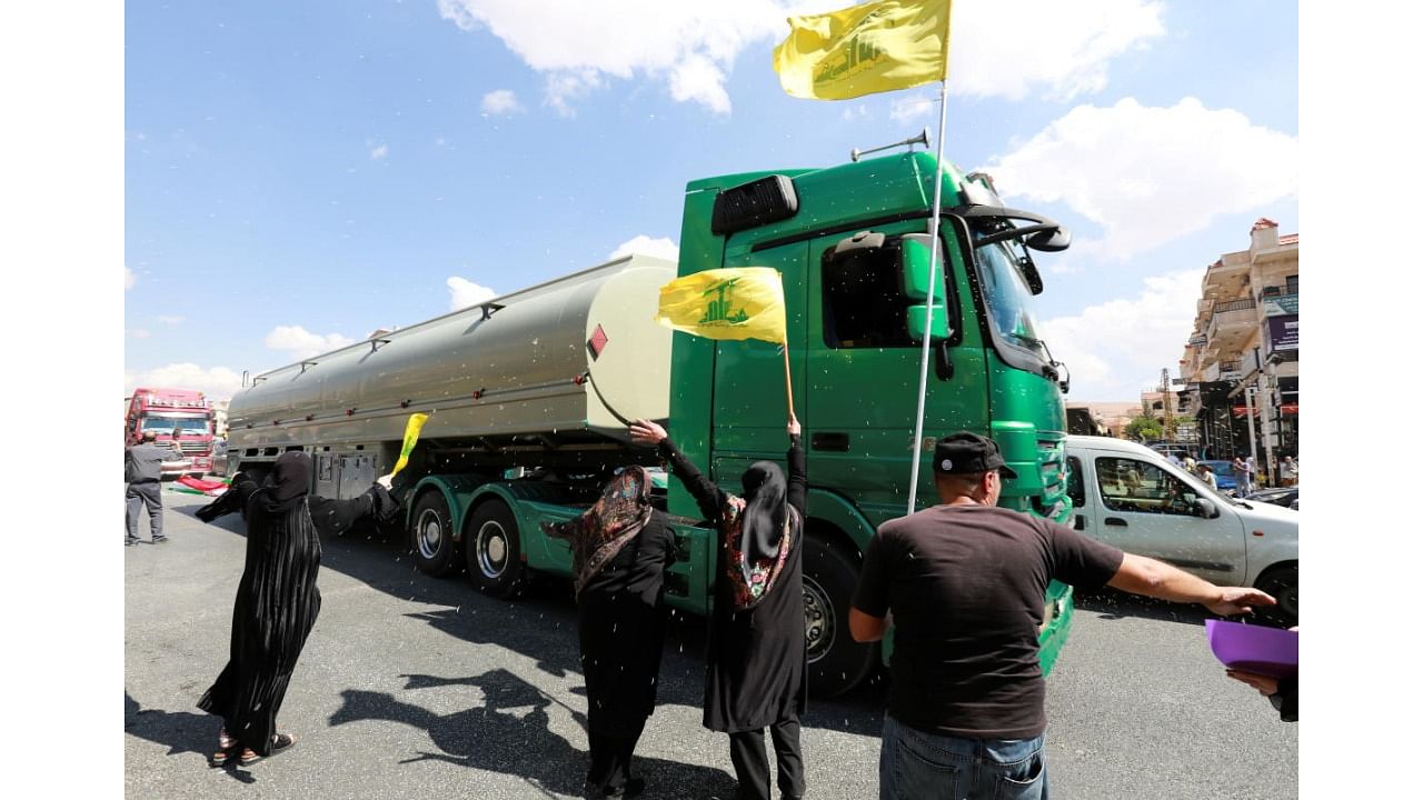 Women hold Hezbollah flags as a convoy of tanker trucks carrying Iranian fuel oil drive in Baalbeck. Credit: Reuters Photo