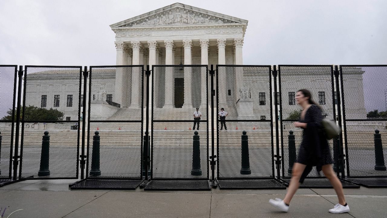 A person walks near security fencing around the Supreme Court in Washington, Friday, September 17, 2021, ahead of a weekend rally planned by allies of Donald Trump that is aimed at supporting the so-called "political prisoners" of the January 6 insurrection at the US Capitol. Credit: AP/PTI File Photo