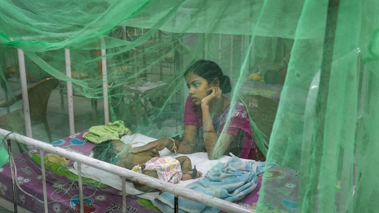 A mother sits alongside her child, who is suffering from Dengue fever. Credit: PTI File Photo