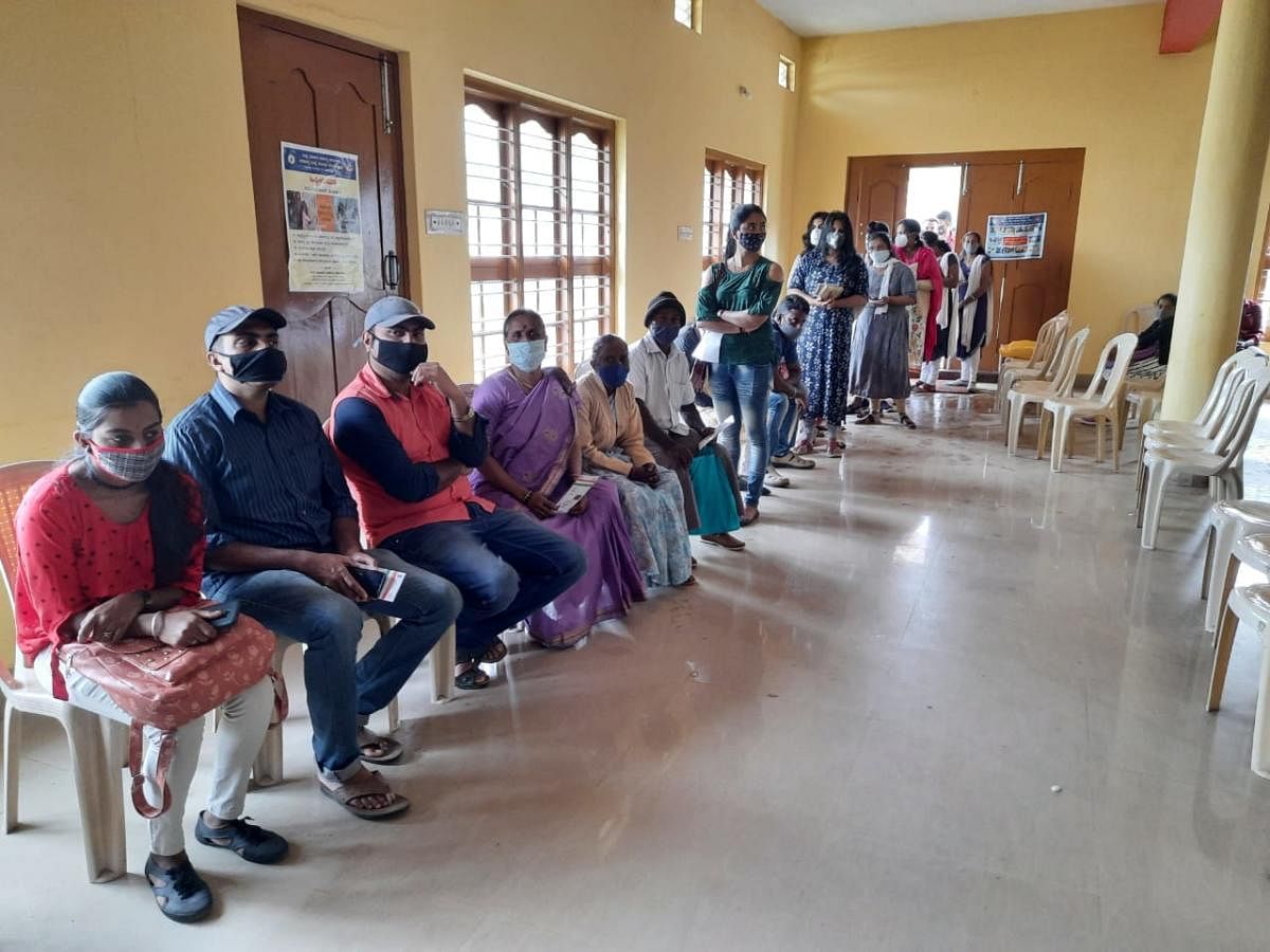 People await their turn at a vaccination centre in Madikeri on Friday. DH Photo