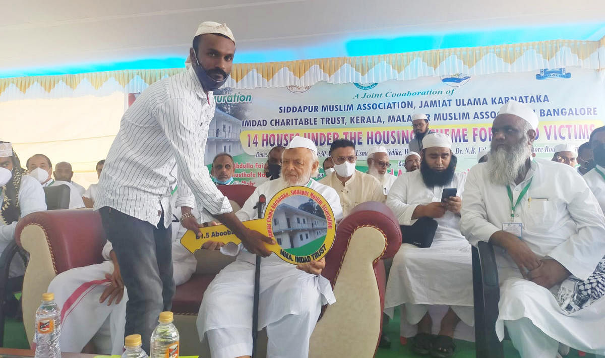 Jamiat Ulema-e-Hind national president Maulana Arshad Madani hands over the key of a house to a beneficiary in Siddapura.