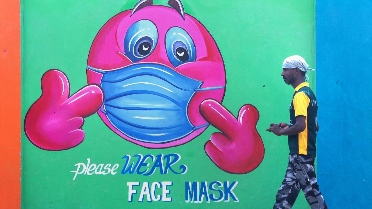 People walk past a wall mural on Covid awareness. Credit: PTI Photo
