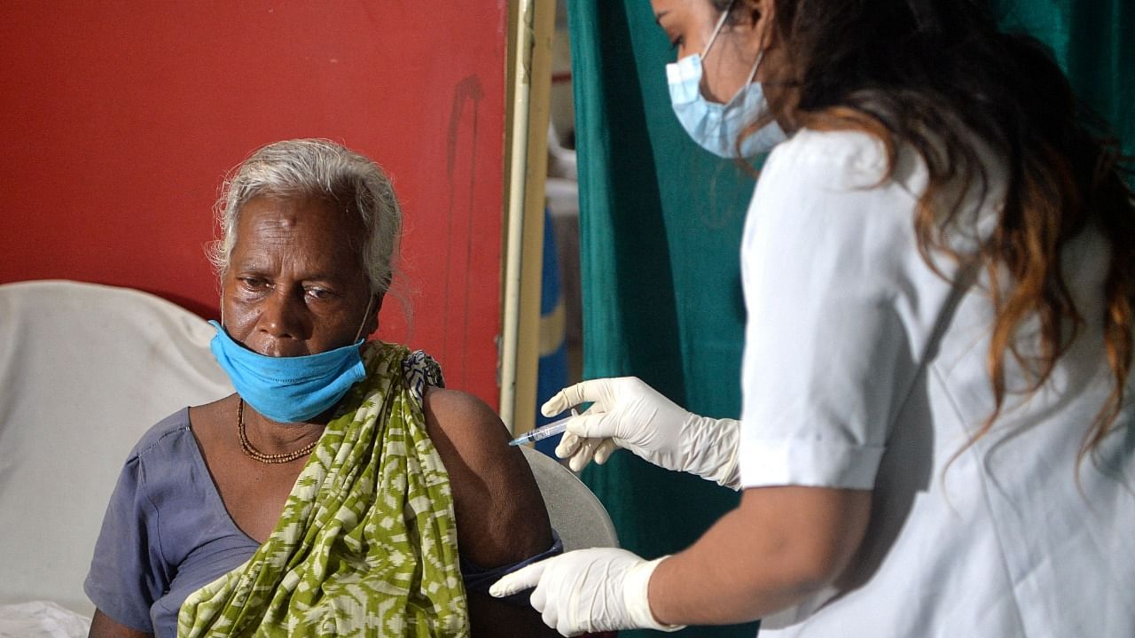 A health worker inoculates an underprivileged woman with a dose of the Covishield vaccine against Covid-19. Credit: AFP File Photo