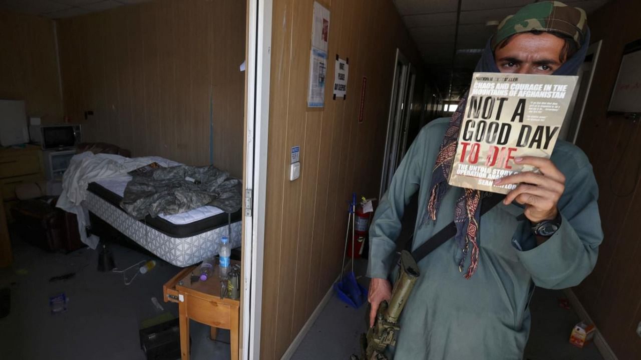 A Taliban fighter holds the book "Not a good day to die" inside an US Army camp at the airport in Kabul. Credit: AFP Photo