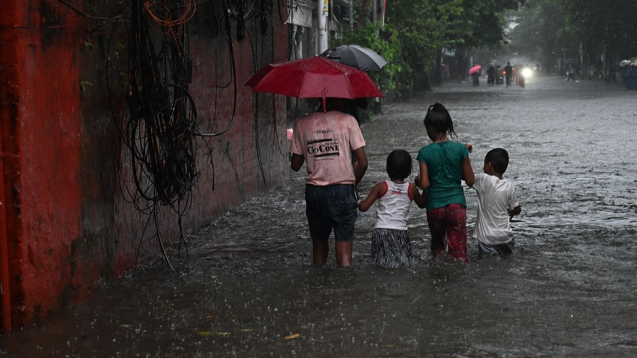 Children wade through a waterlogged street after heavy rainfall in Kolkata. Credit: AFP Photo
