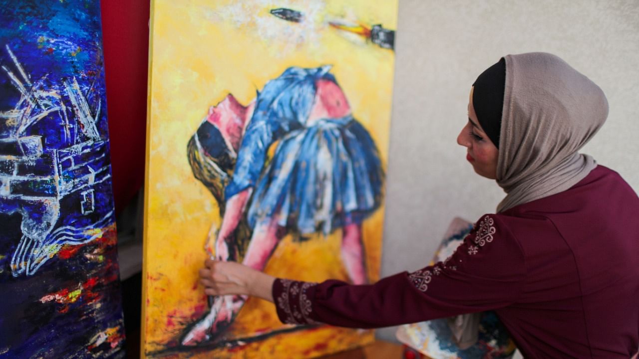 A Palestinian artist, Abeer Jibril, works on ballet paintings at her home in Gaza City, September 8, 2021. Credit: Reuters Photo