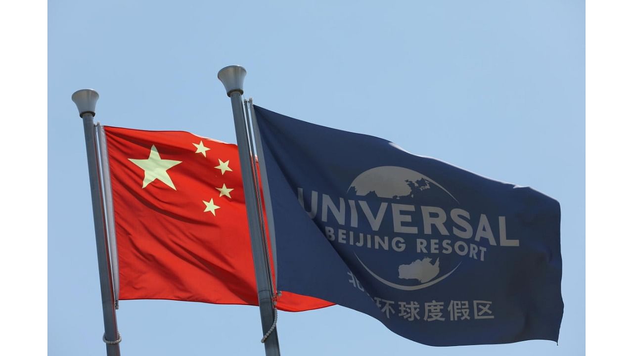 Chinese national flag flutters next to a flag of Universal Beijing Resort. Credit: Reuters File Photo