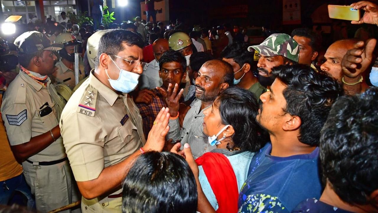 A police officer tries to pacify angry residents in Sanjaynagar, Bengaluru, on Sunday night. Credit: DH Photo/Krishnakumar P S