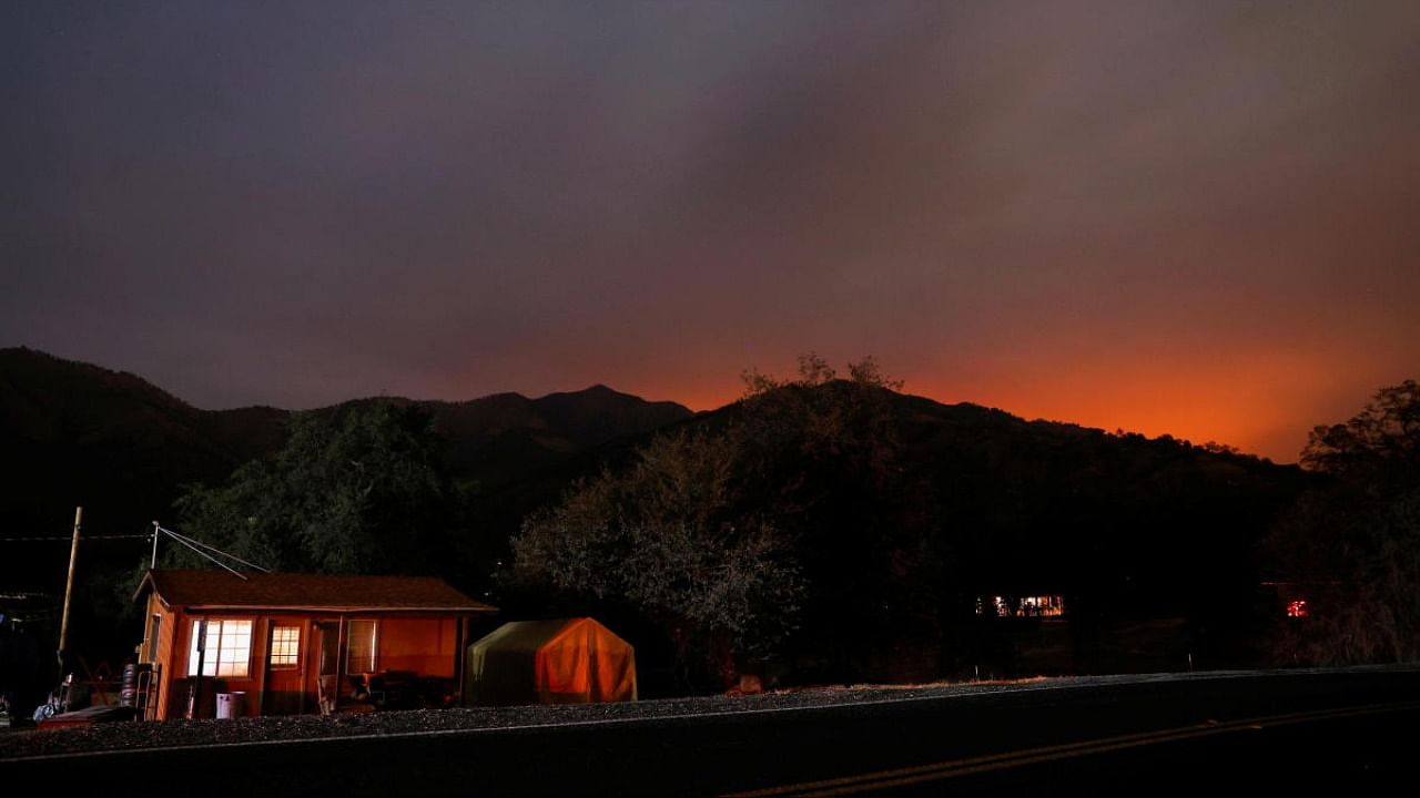 The glow from the KNP Complex fire burning in Sequoia National Park is seen in the hills behind homes in Three Rivers, California. Credit: Reuters file photo