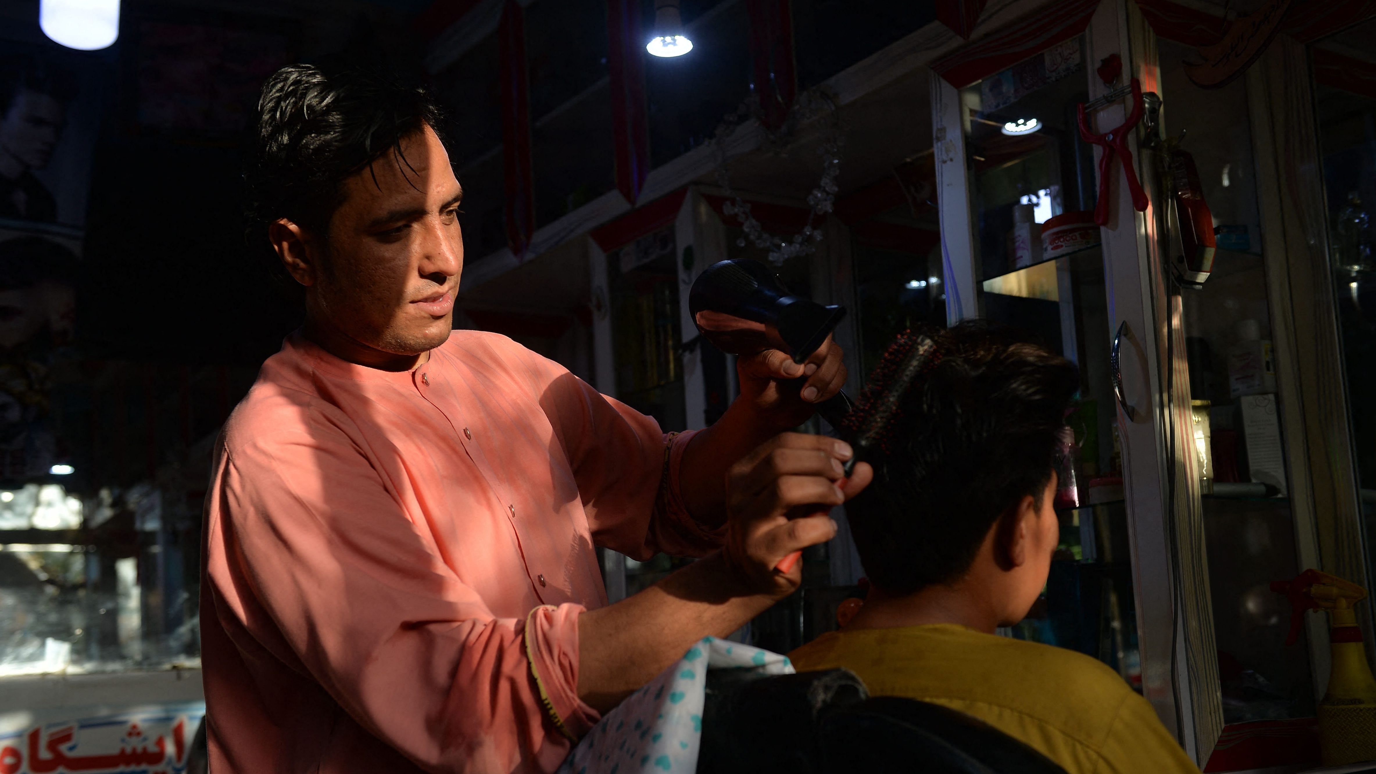 24-year-old Nader Shah (L) attends a customer at his barbershop in Herat. Credit: AFP Photo