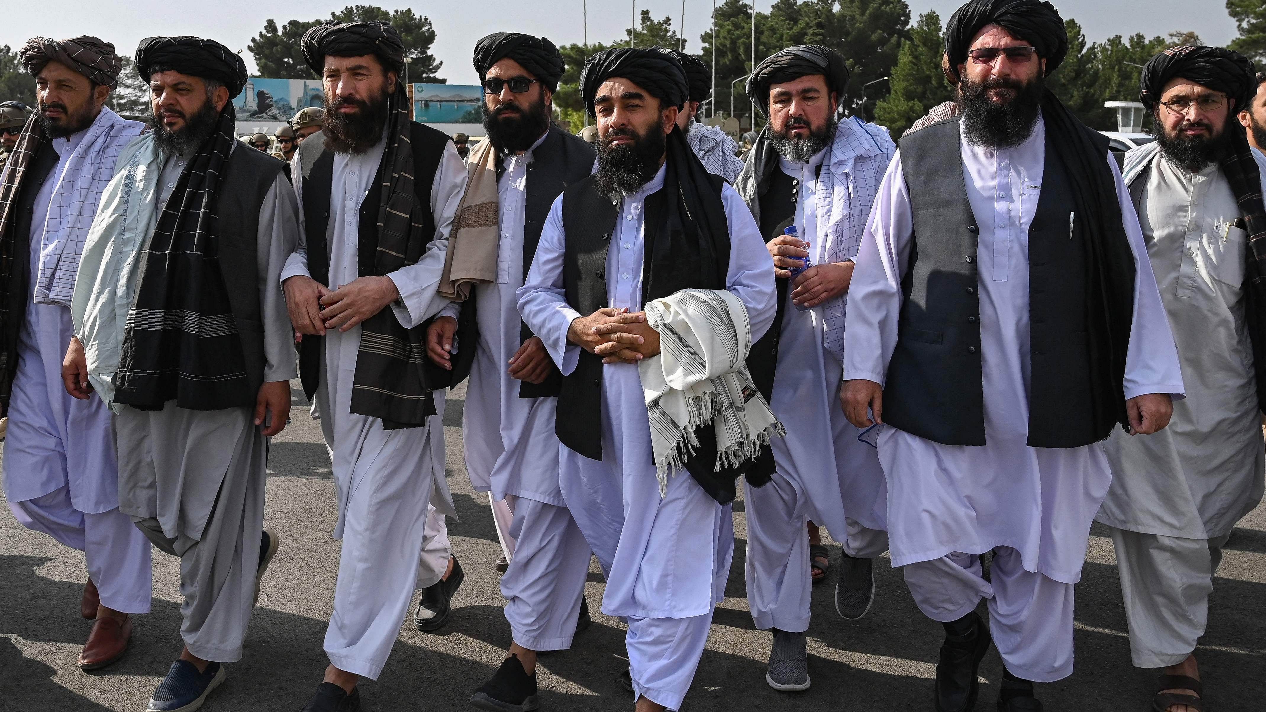 Taliban spokesman Zabihullah Mujahid (C, holding shawl) arrives as he is accompanied by officials to address a media conference. Credit: AFP File Photo