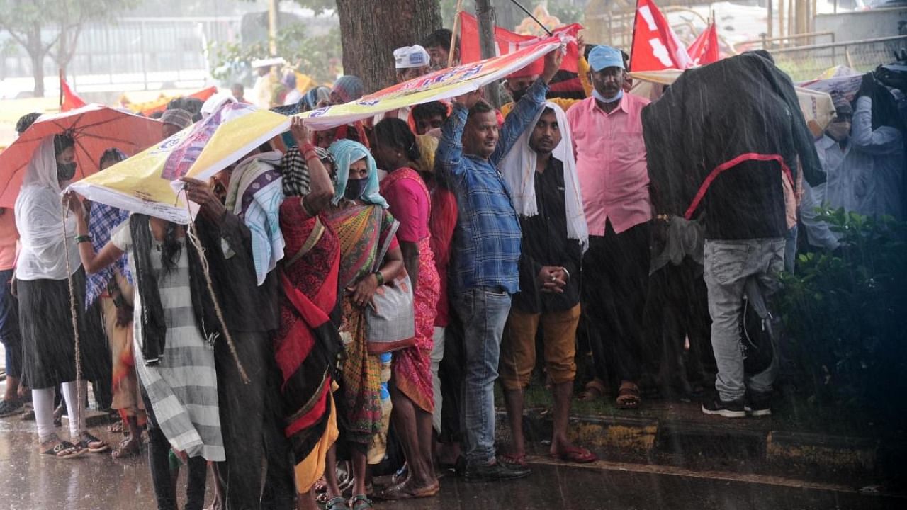 Protesters take shelter at Freedom Park during the downpour on Monday. Credit: DH Photo