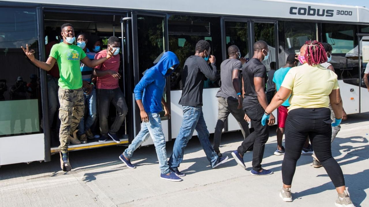 Haitian migrants get off an aiport bus after US authorities flew them out of a Texas border city where thousands of mostly Haitians had gathered under a bridge after crossing the Rio Grande river from Mexico, in Port-au-Prince, Haiti. Credit: Reuters photo