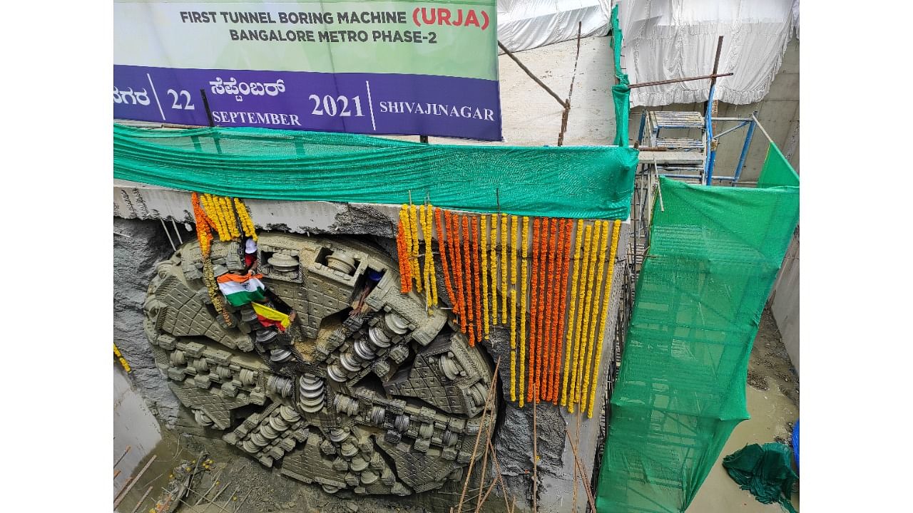 Workers hold Tricolour and Kannada flags as TBM Urja makes a breakthrough for the Namma Metro Phase 2's Reach 6 line at Shivajinagar on Wednesday. Credit: DH Photo