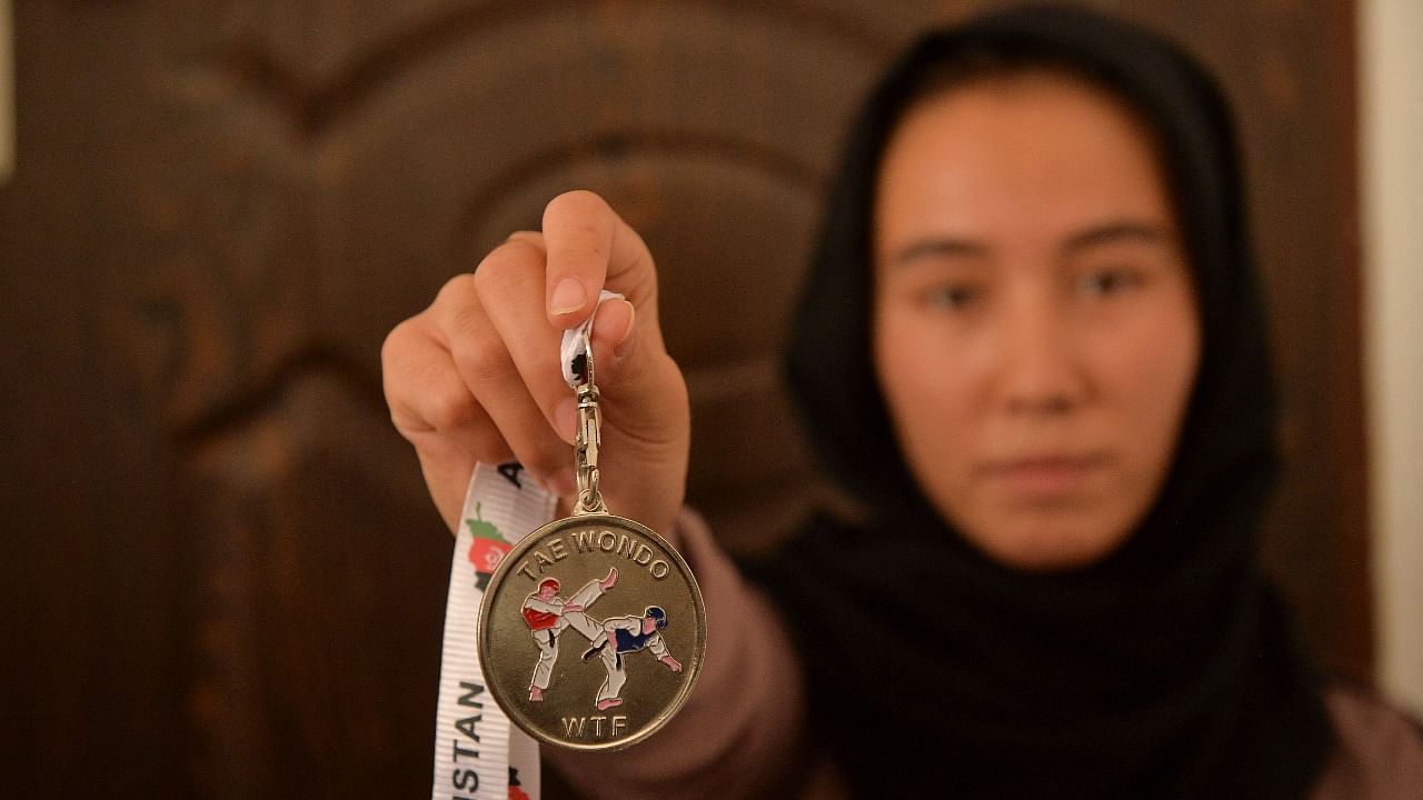This picture taken on September 21, 2021 shows taekwondo champion Zarghunna Noori showing her medal at a house in Herat province. Credit: AFP Photo