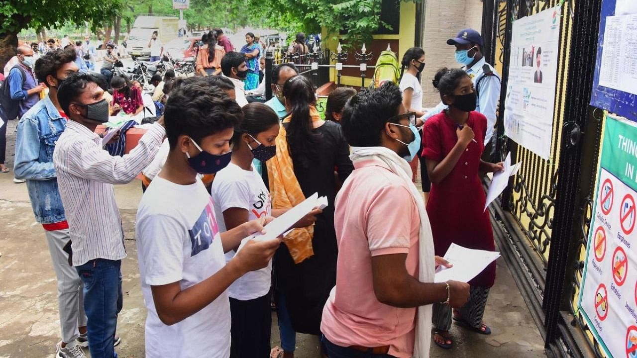 Aspirants look for their seat number to enter an examination centre for appearing in National Eligibility cum Entrance Test (NEET UG 2021), in Jabalpur. Credit: PTI Photo