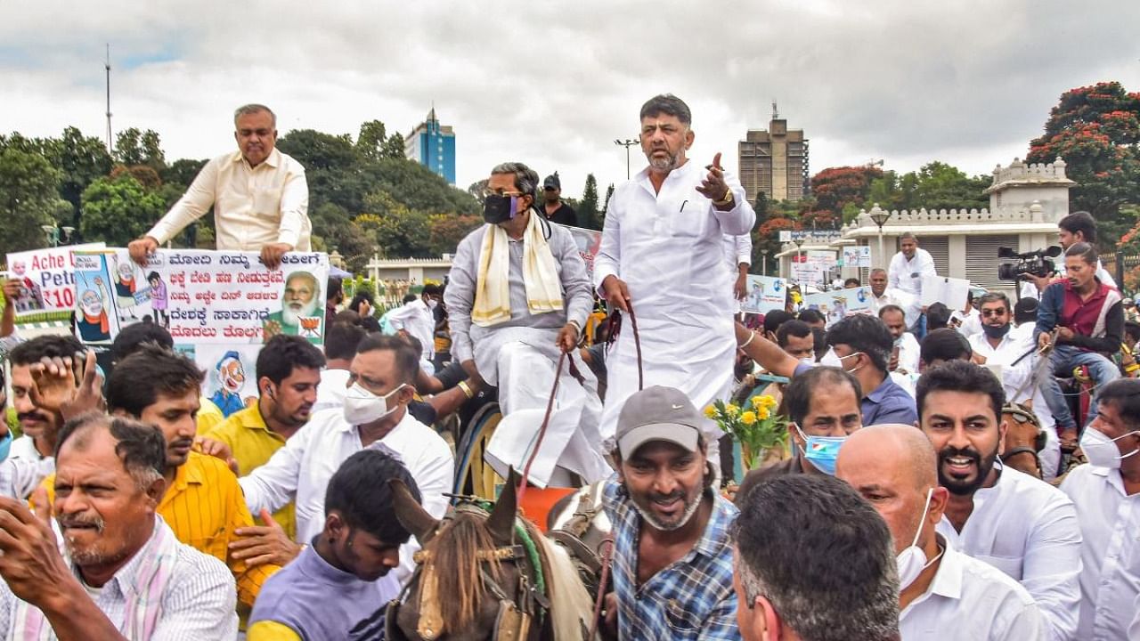 Opposition leader in the Karnataka Assembly Siddaramaiah and KPCC President D K Shivakumar ride on a bullock cart to reach Vidhanasoudha for the assembly session, in Bengaluru. Credit: PTI Photo