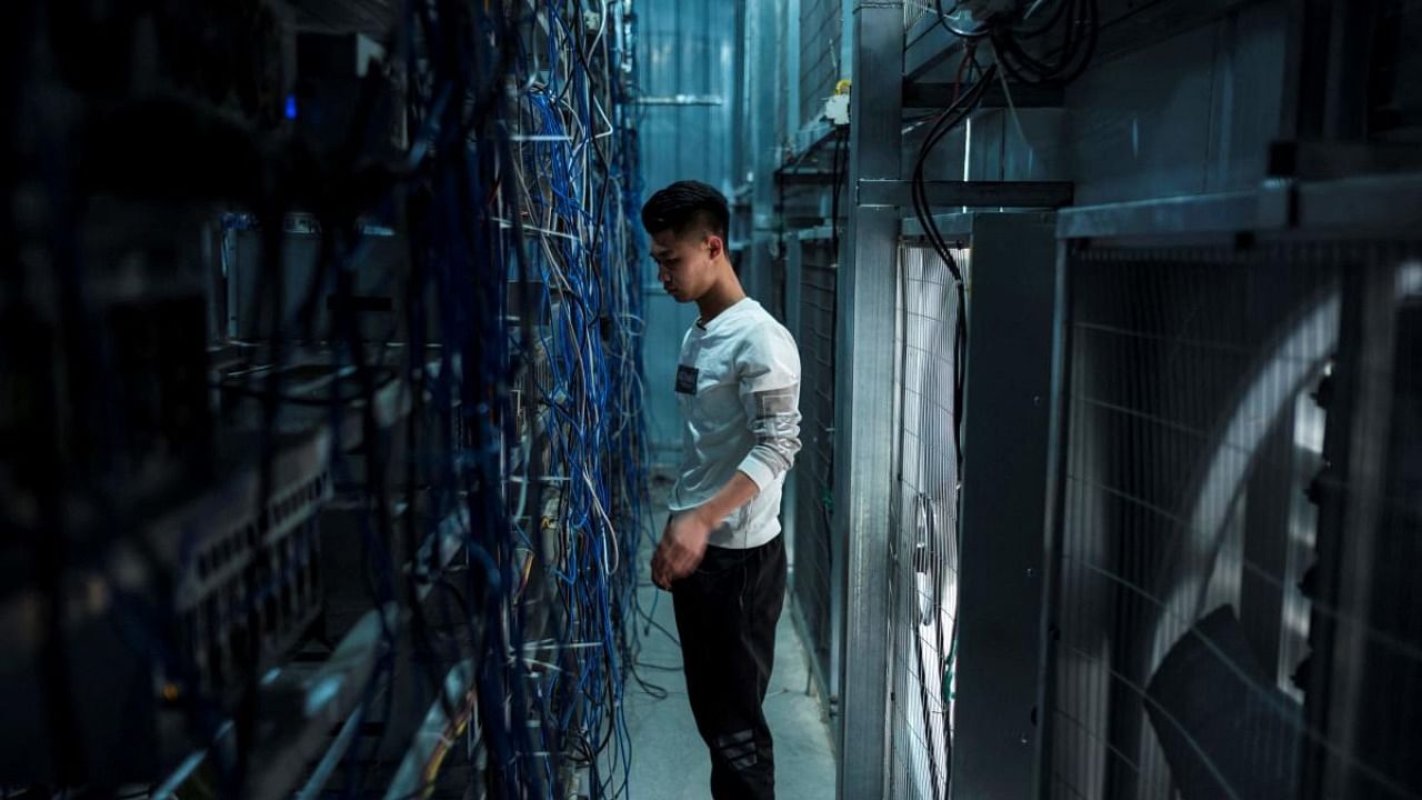 A worker adjusts cryptocurrency mining rigs at a cryptocurrency farm in Dujiangyan in China's southwestern Sichuan province. Credit: AFP Photo