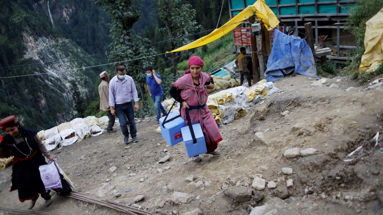 Phula Devi, 30, a local health worker carries boxes containing COVISHIELD vaccine, at Malana village in Kullu district in the Himalayan state of Himachal Pradesh, India. Credit: Reuters photo