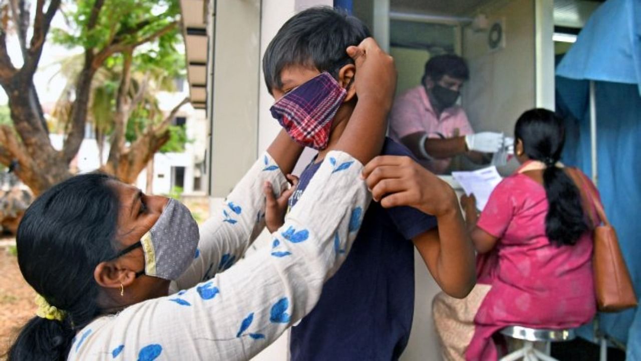 A woman puts a mask on her child at CV Raman General Hospital. Credit: DH File Photo